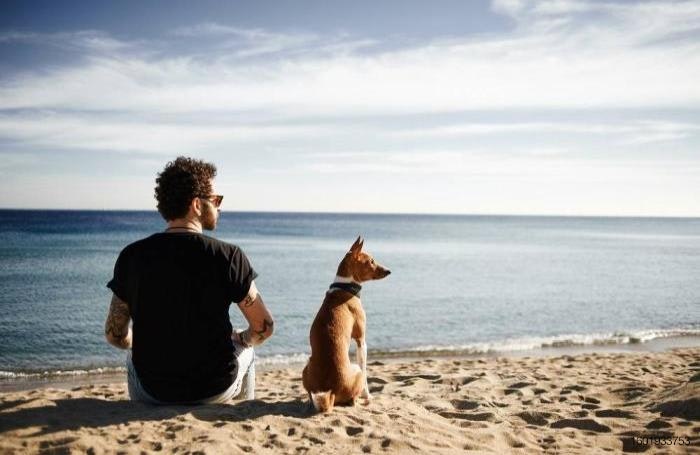 Millennial man and dog at the beach