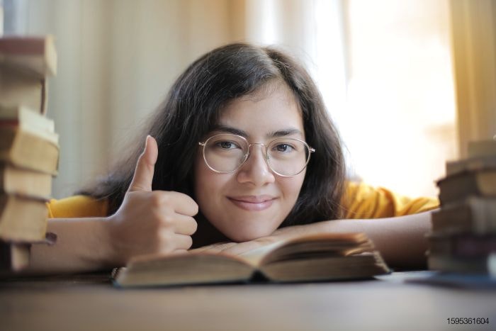 Thumbs up student on books