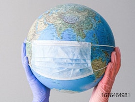 World globe being held by gloved hands and wearing a mask